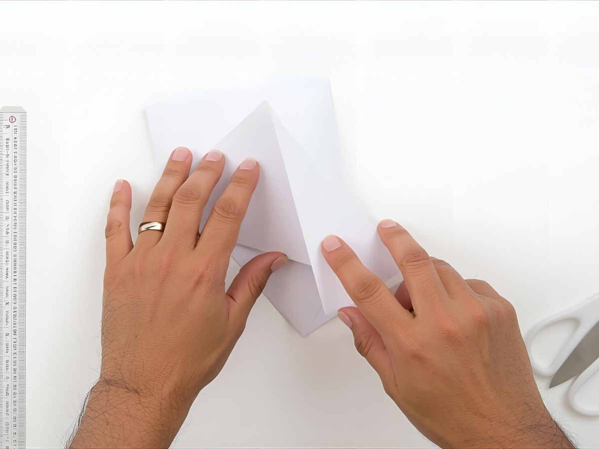 Hands folding a piece of cardstock into a greeting card shape.